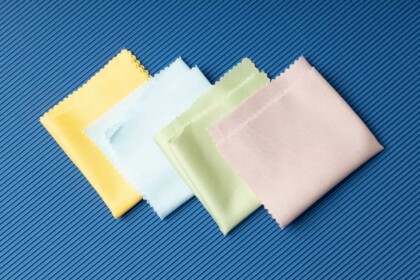 Pastel-colored microfiber cloths arranged on textured blue background.