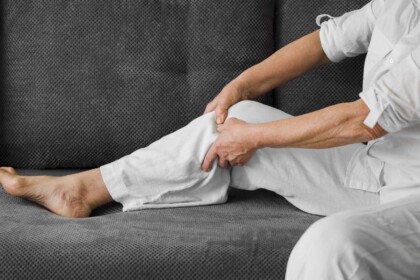 Senior massaging leg on couch, indicating discomfort.