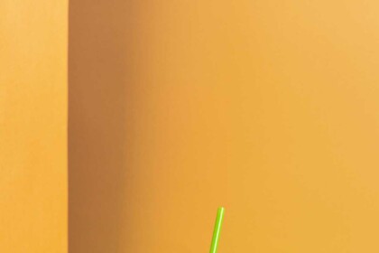 Pink soda can with green straw on dual-tone background.
