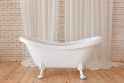 White vintage clawfoot bathtub in a rustic brick-walled bathroom.
